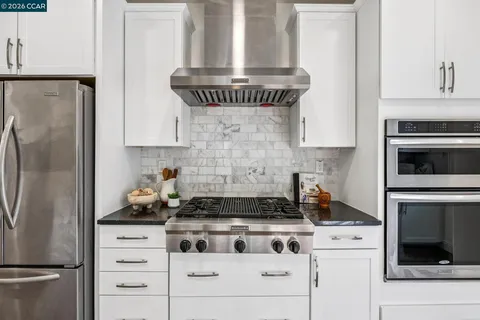 a kitchen with a stove and white cabinets