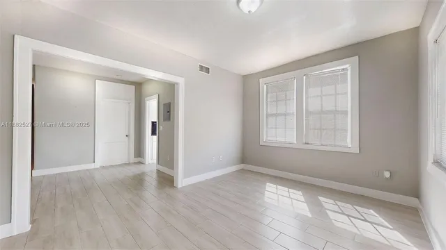 a view of an empty room with wooden floor and a window