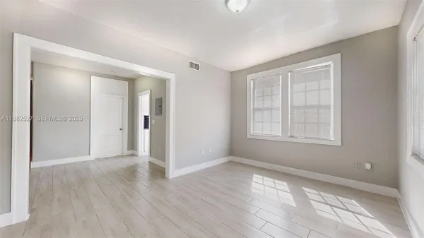 a view of an empty room with wooden floor and a window