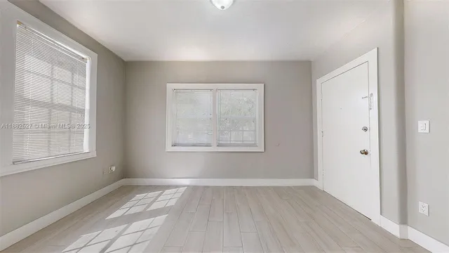 a view of an empty room with wooden floor and a window