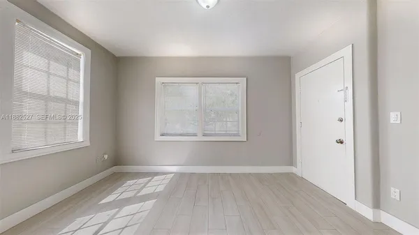 a view of an empty room with wooden floor and a window