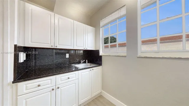 a kitchen with granite countertop white cabinets and sink