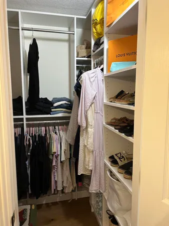 a view of walk in closet with clothes and shoes