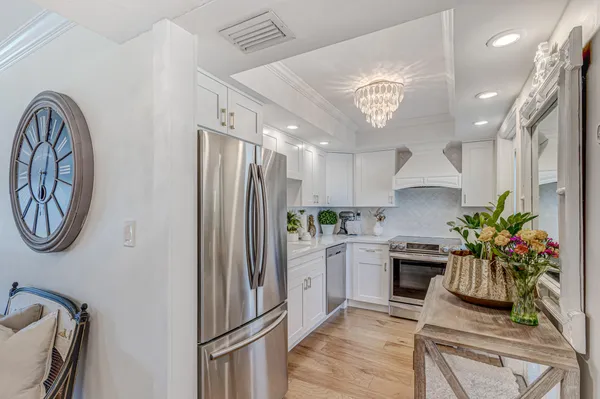 a kitchen with stainless steel appliances a refrigerator a sink a stove and white cabinets