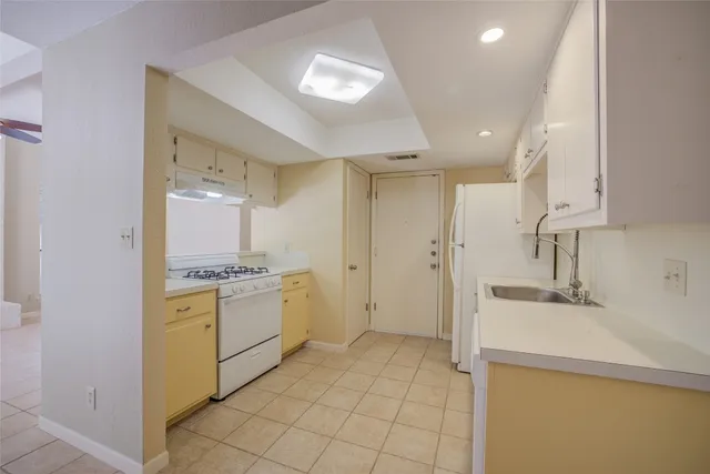 a room with a sink a stove a refrigerator and cabinets