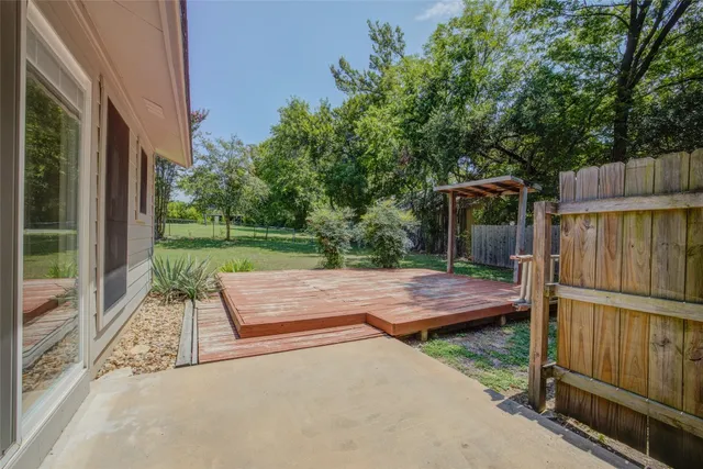 a view of backyard with wooden fence and large trees