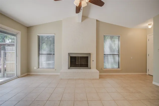 an empty room with windows and fireplace