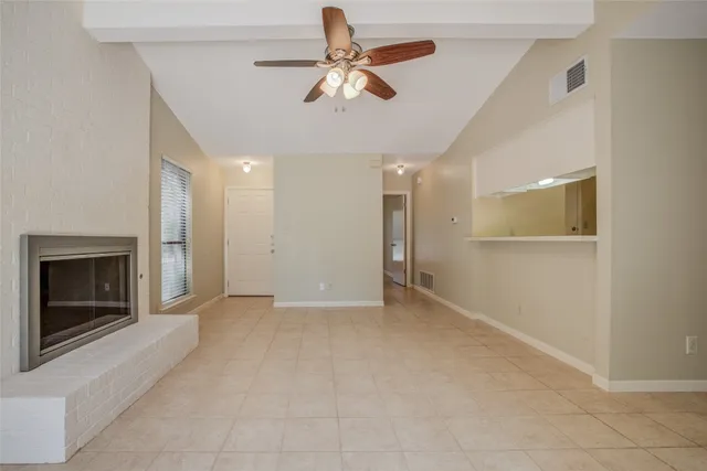 an empty room with chandelier fan and windows