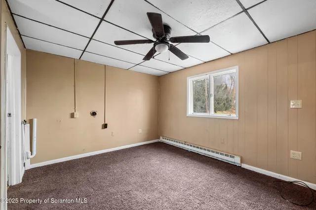 an empty room with wooden floor ceiling fan and windows