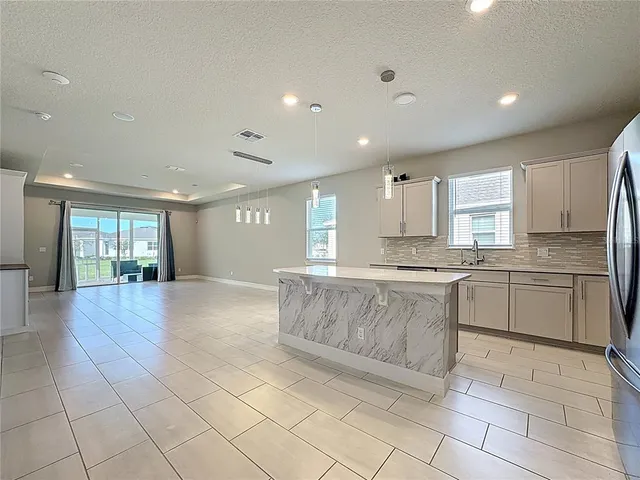 a large white kitchen with kitchen island granite countertop a stove a sink a window and white cabinets