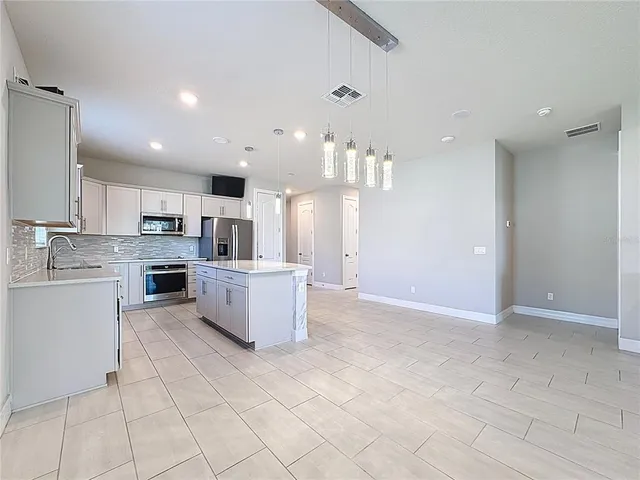 a kitchen with stainless steel appliances kitchen island granite countertop a refrigerator and a stove top oven