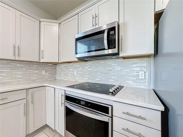 a kitchen with granite countertop white cabinets stainless steel appliances and a sink