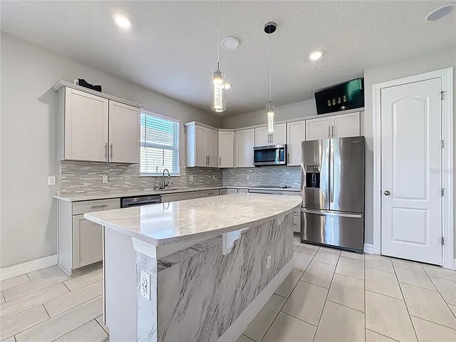 a large kitchen with granite countertop a refrigerator and a sink