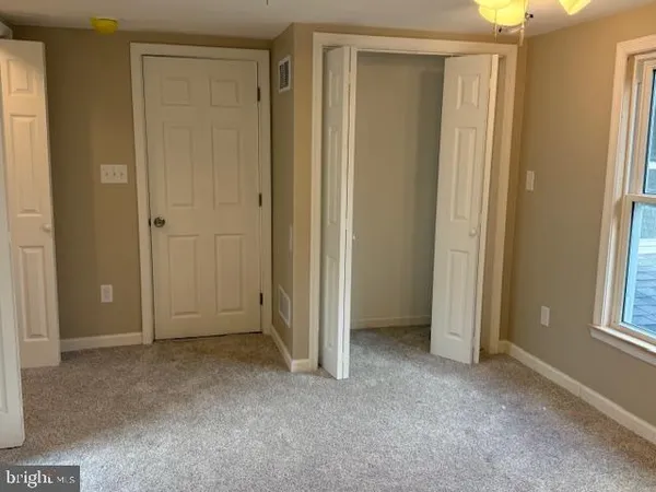 a view of an empty room with windows and closet