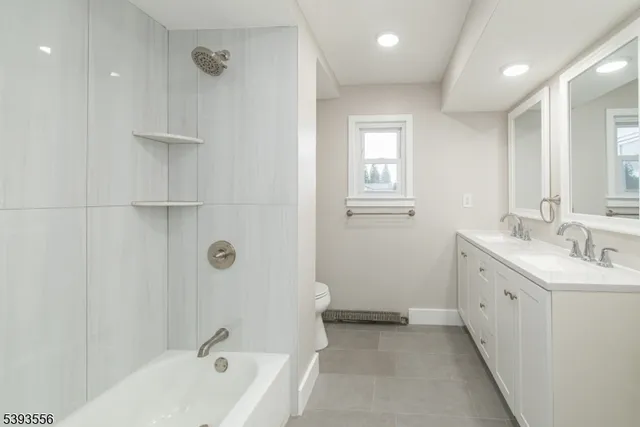 a bathroom with a double vanity sink large mirror and a bathtub