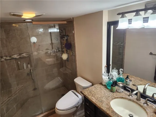 a bathroom with a granite countertop toilet a sink and shower