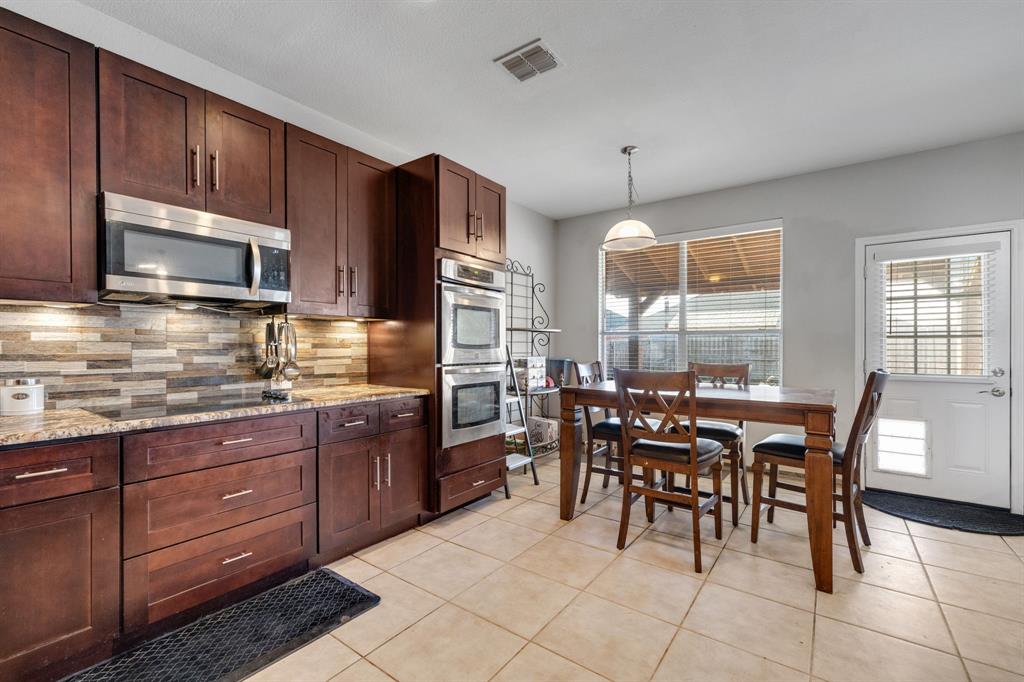 4029 Bridge Water Road Heartland, TX 75126 - Photo 12 of 39 a kitchen with a stove a sink a dining table and chairs