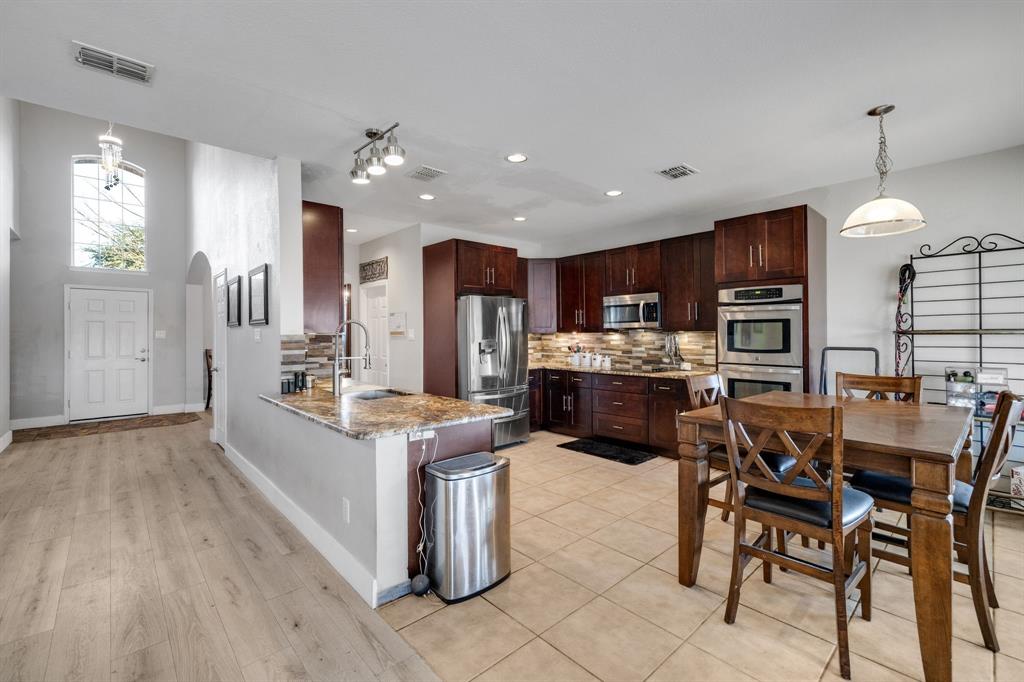 4029 Bridge Water Road Heartland, TX 75126 - Photo 14 of 39 a kitchen with stainless steel appliances kitchen island granite countertop a table chairs and a refrigerator