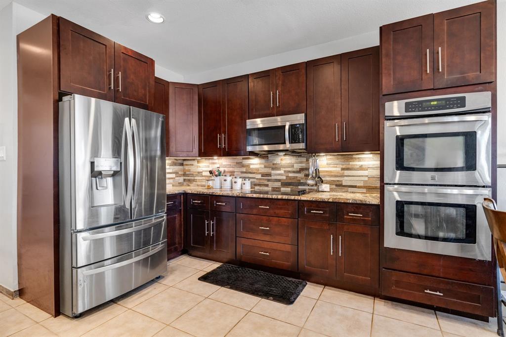4029 Bridge Water Road Heartland, TX 75126 - Photo 4 of 39 a kitchen with granite countertop wooden cabinets a refrigerator and a stove top oven