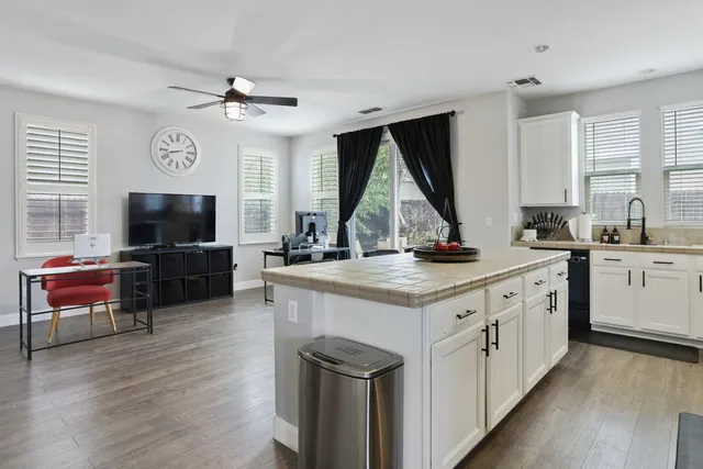 a kitchen with a refrigerator a stove a sink and a dining table with wooden floor