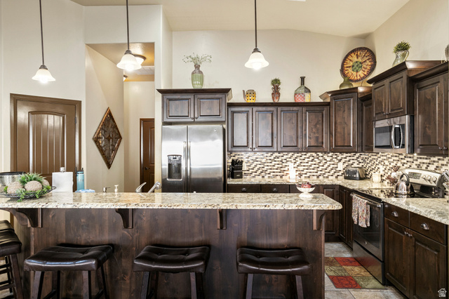210 Talon Court Ivins, UT 84738 - Photo 19 of 60 Kitchen featuring dark wood finish cabinetry, stainless steel appliances, a kitchen bar, and light stone countertops