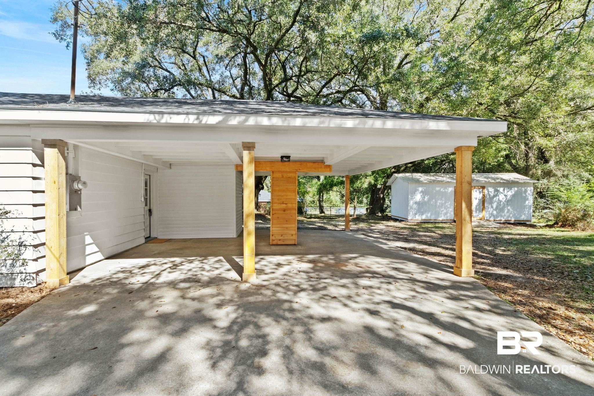 618 Pine Street Saraland, AL 36571 - Photo 29 of 41 View of parking / parking lot featuring an attached carport, concrete driveway, and a shed