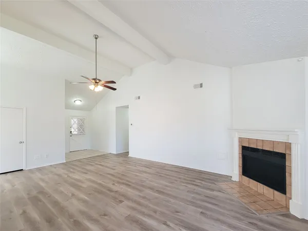 a view of a room with wooden floor a ceiling fan and a window