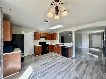 a kitchen with stainless steel appliances granite countertop a refrigerator a stove top oven a sink dishwasher and wooden floor