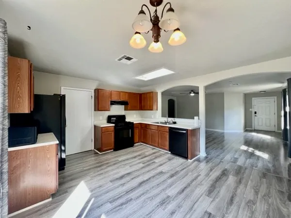 a kitchen with stainless steel appliances granite countertop a refrigerator a stove top oven a sink dishwasher and wooden floor