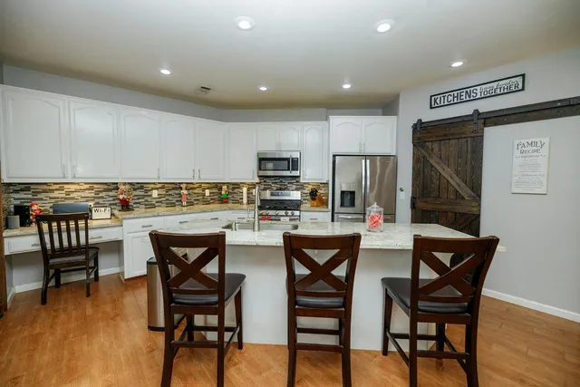 a kitchen with stainless steel appliances granite countertop a table chairs sink refrigerator and cabinets