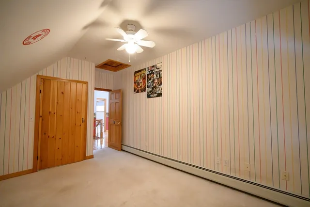 an empty room with chandelier fan and windows