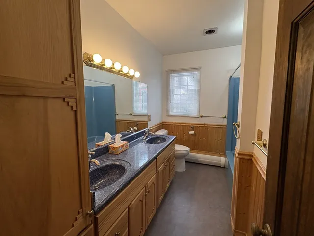 a bathroom with a double vanity sink toilet and mirror