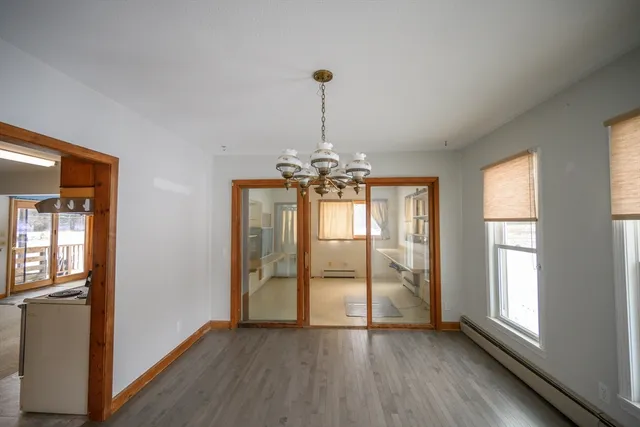 a view of a room with wooden floor chandelier and windows