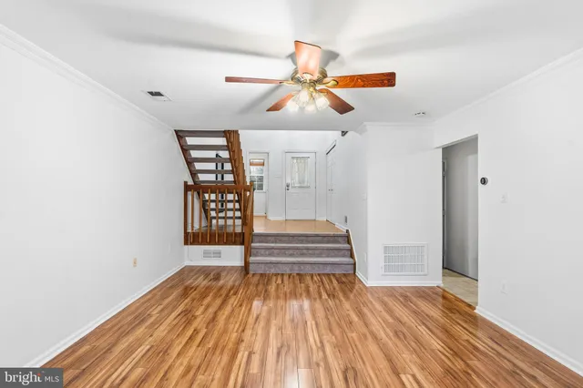 a view of empty room with wooden floor and fan