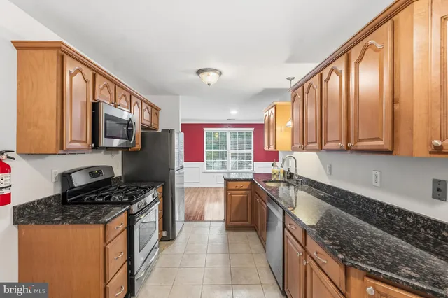 a kitchen with stainless steel appliances granite countertop a stove top oven a refrigerator and a microwave