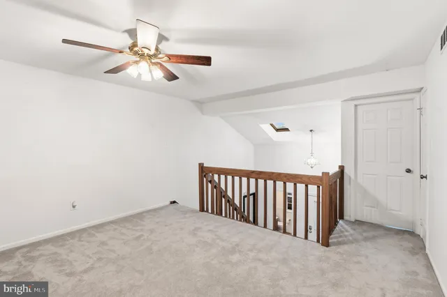 an empty room with ceiling fan and windows