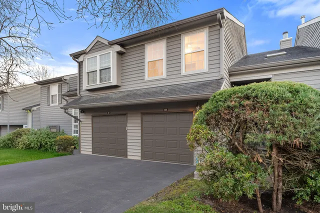 an empty room with wooden floor a ceiling fan a fireplace and windows