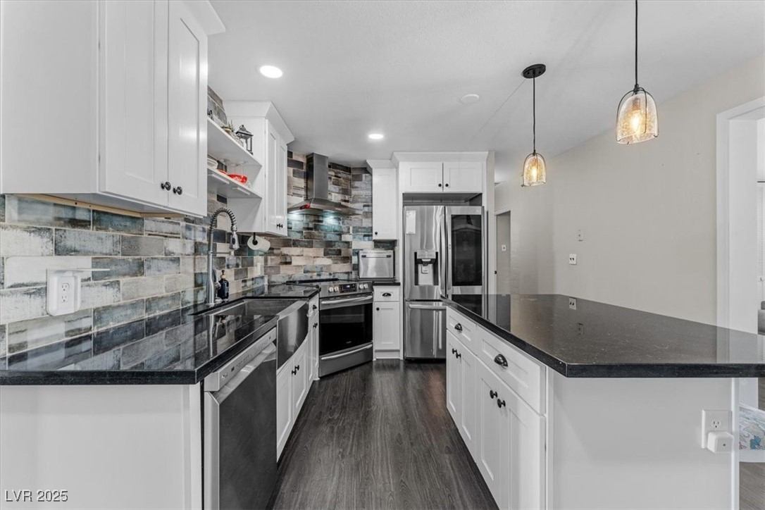 556 7th Street Boulder City, NV 89005 - Photo 5 of 37 Kitchen featuring open shelves, tasteful backsplash, stainless steel appliances, wall chimney exhaust hood, and decorative light fixtures