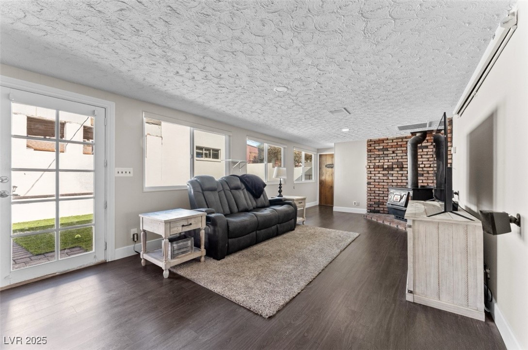 556 7th Street Boulder City, NV 89005 - Photo 7 of 37 Living area featuring a wood stove, dark wood-style floors, and a textured ceiling