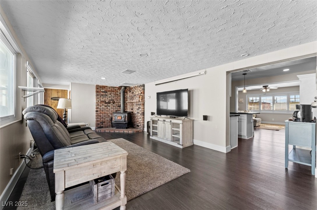 556 7th Street Boulder City, NV 89005 - Photo 8 of 37 Living room featuring a wood stove, dark wood-style floors, a ceiling fan, and a textured ceiling