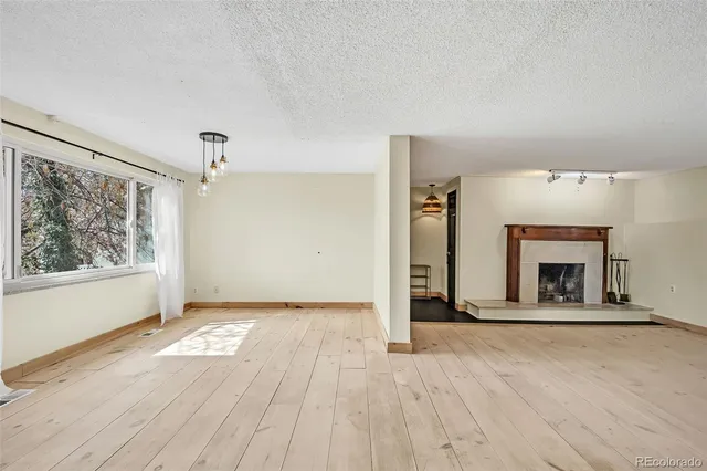a view of an empty room with a fireplace and a window