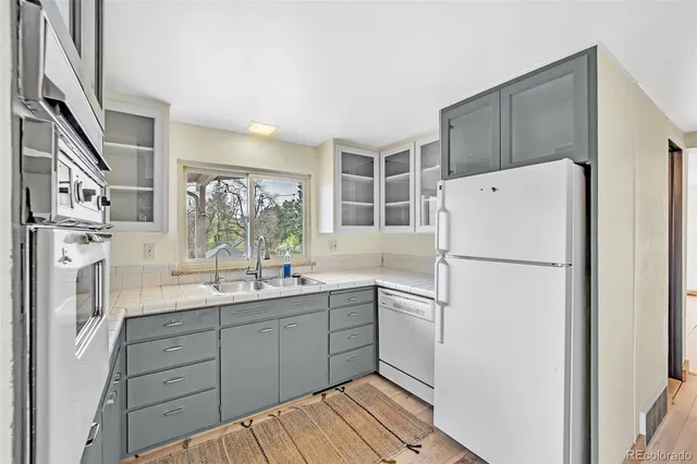 a kitchen with a sink a refrigerator a stove and white cabinets