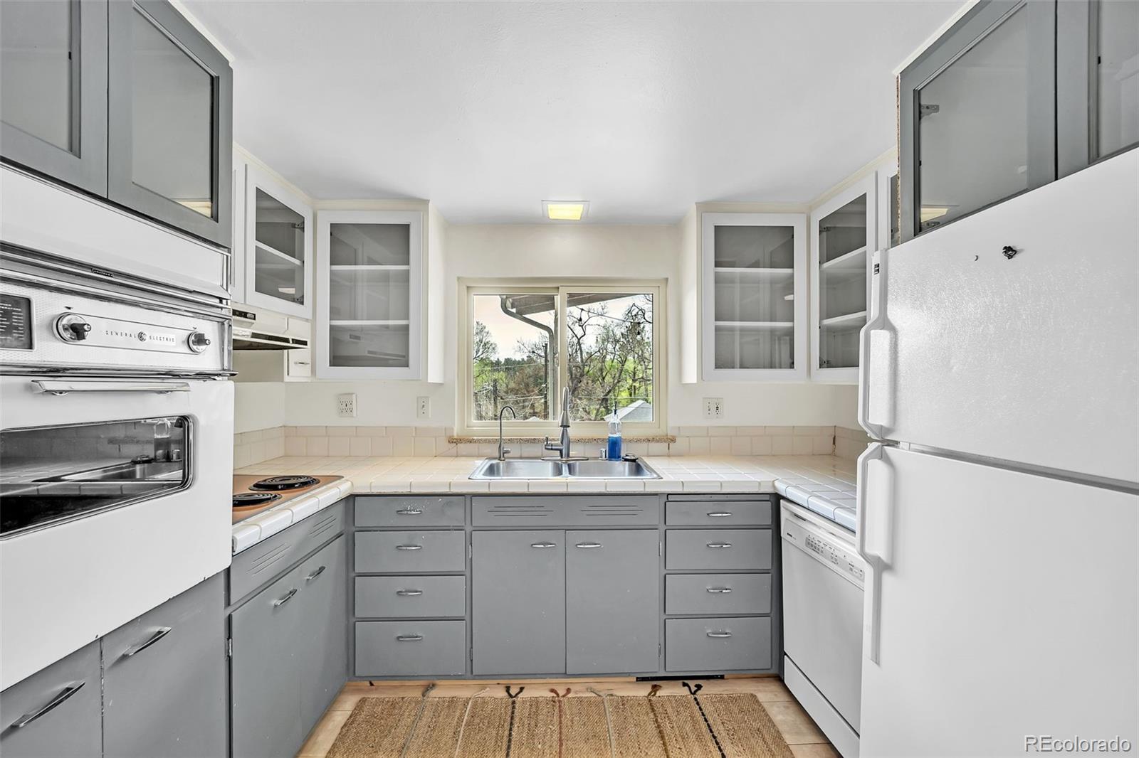 1624 Cheyenne Boulevard Colorado Springs, CO 80906 - Photo 24 of 47 a kitchen with a sink a refrigerator a stove and white cabinets