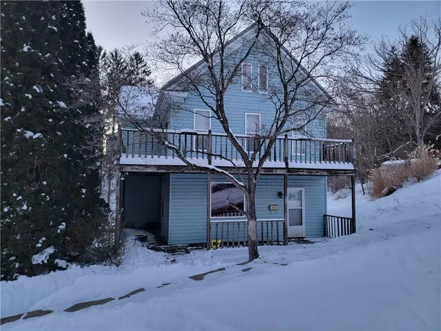 a view of a house with large trees and wooden fence