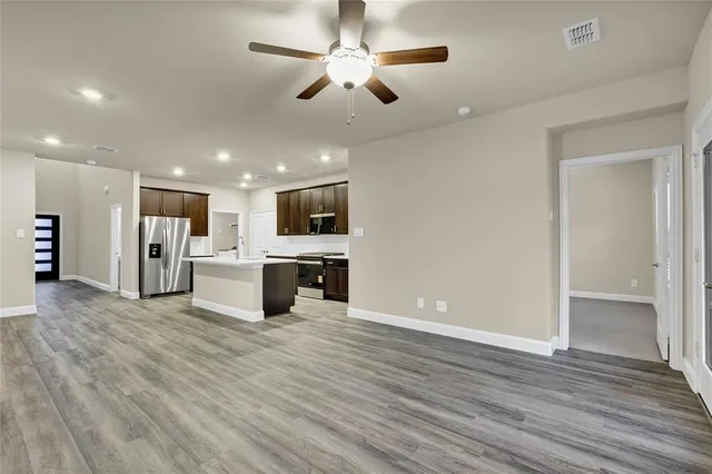 an open kitchen with a refrigerator and microwave area with wooden floor