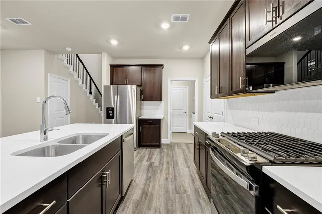 a kitchen with stainless steel appliances a sink stove and refrigerator