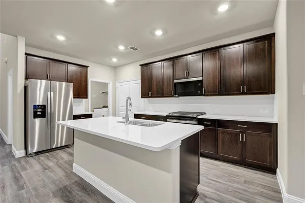 a kitchen with kitchen island granite countertop stainless steel appliances and wooden cabinets