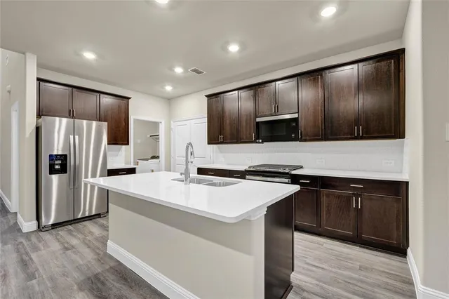 a kitchen with kitchen island granite countertop stainless steel appliances and wooden cabinets