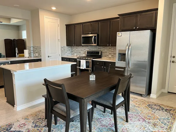 a kitchen with stainless steel appliances a table chairs microwave and refrigerator