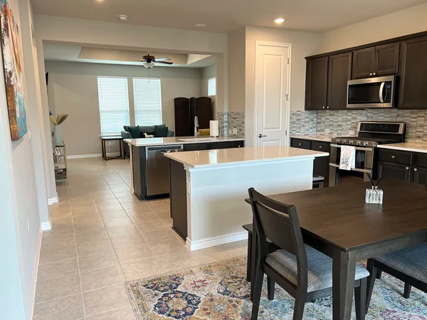 a kitchen with a dining table chairs and refrigerator